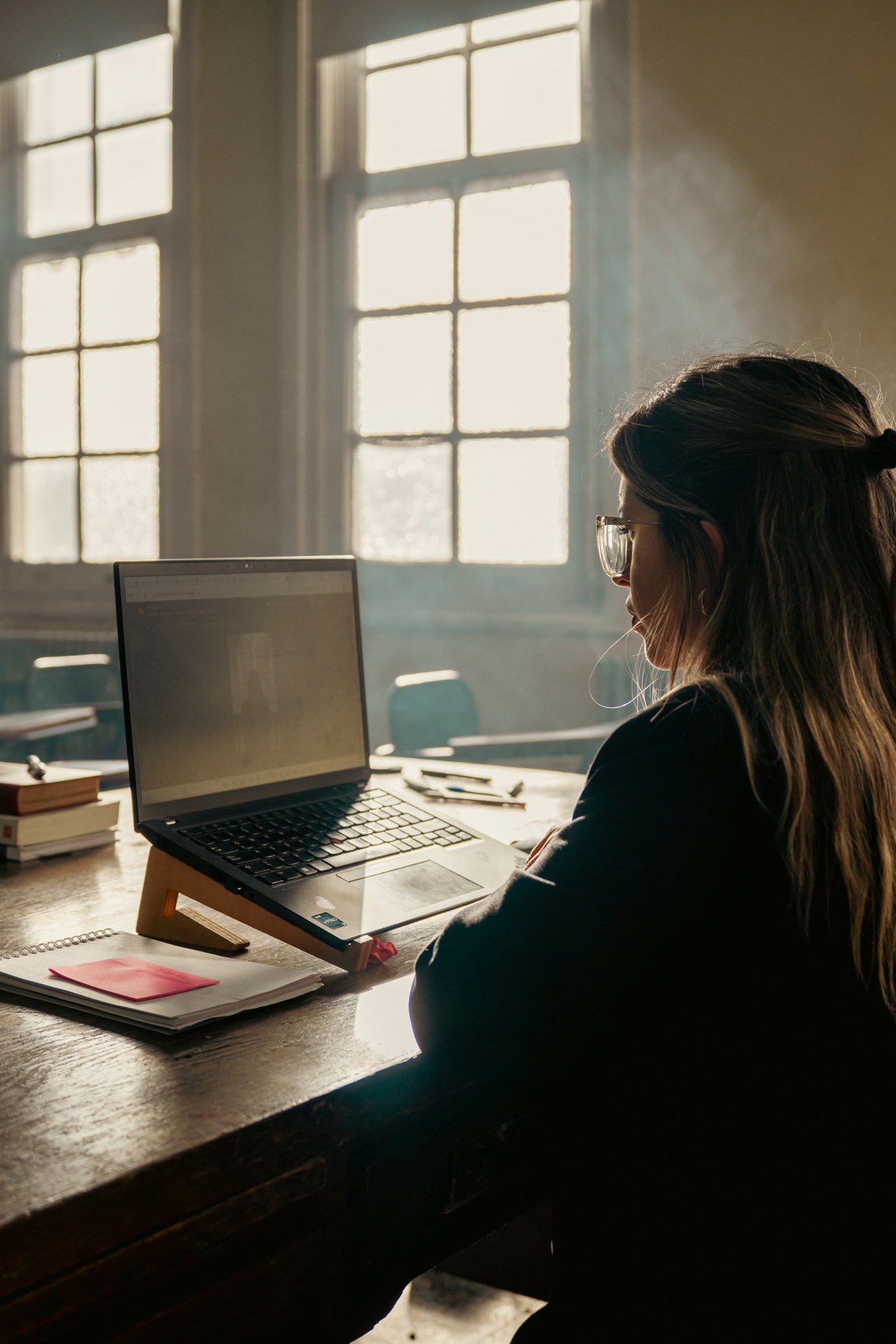 A student working with a laptop in a sunny classroom